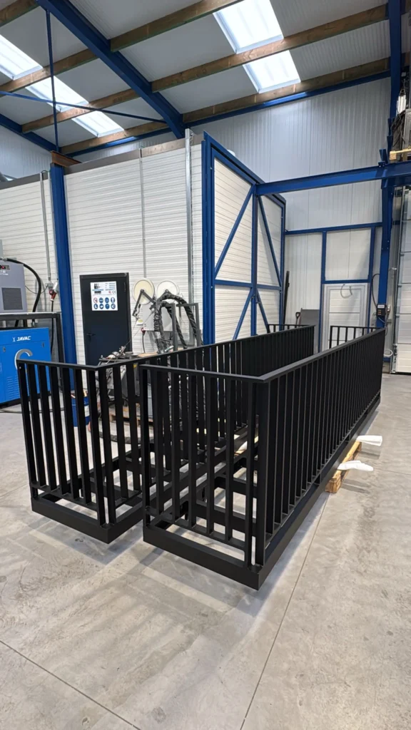 Twee gemetalliseerde balustrades met zwarte poedercoating, opgesteld in de poederlakafdeling van Vlaeminck Poederlakken.